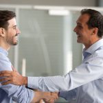 Dois homens de camisa social se cumprimentam