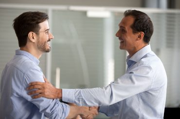 Dois homens de camisa social se cumprimentam