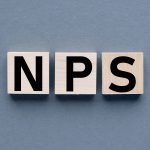 3 cubos de madeira, cada um representando uma letra da sigla NPS sobre um fundo cinza